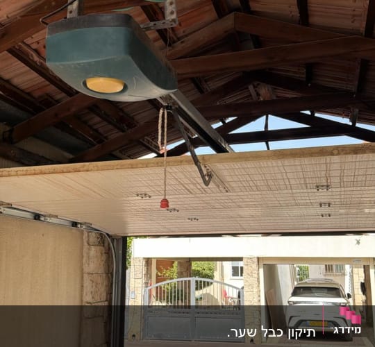 מנגנון שער חשמלי בתוך חניה עם רכב